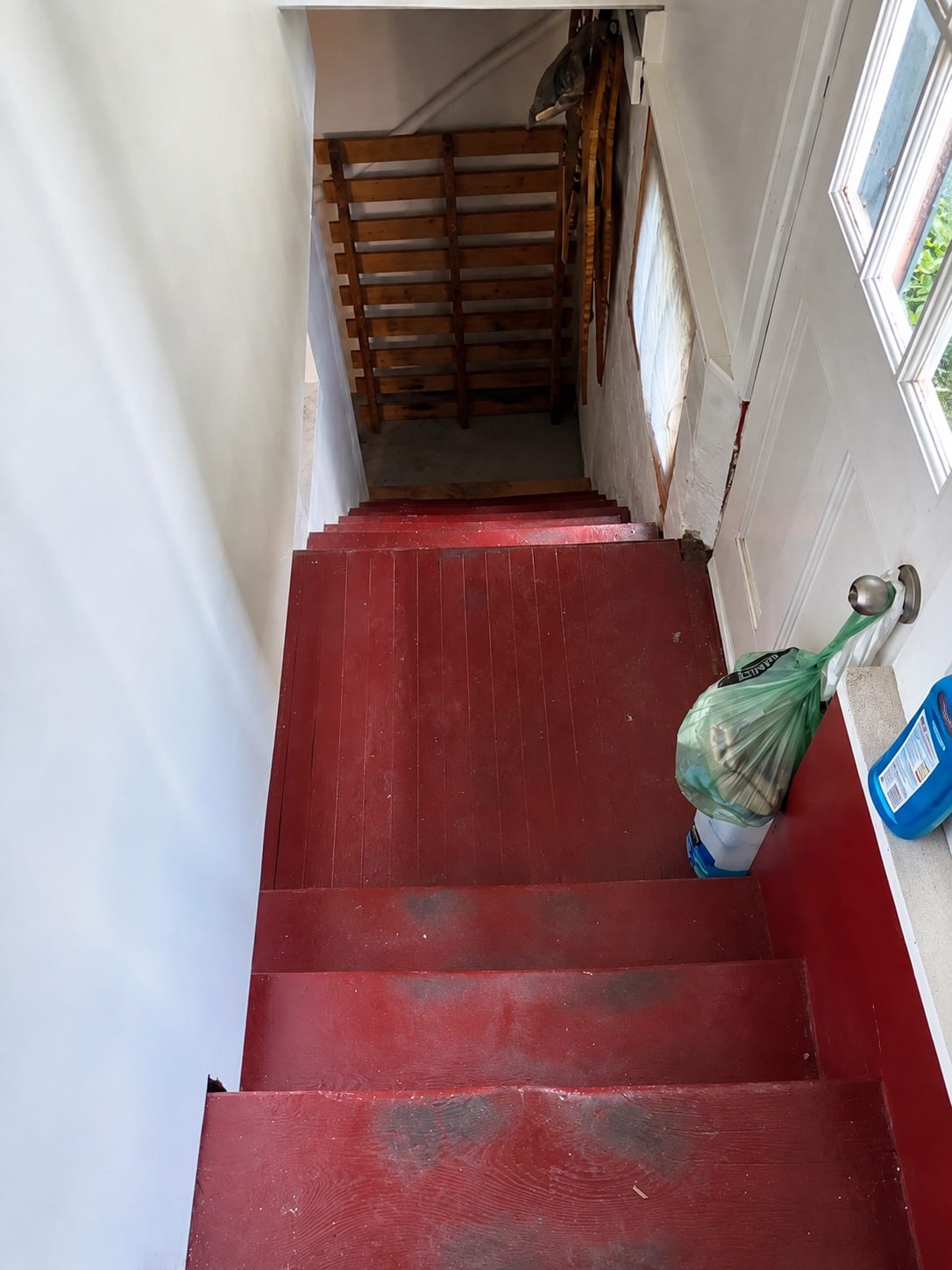 Basement stairs before work: dark red floor paint worn through to bare wood on the treads and landing