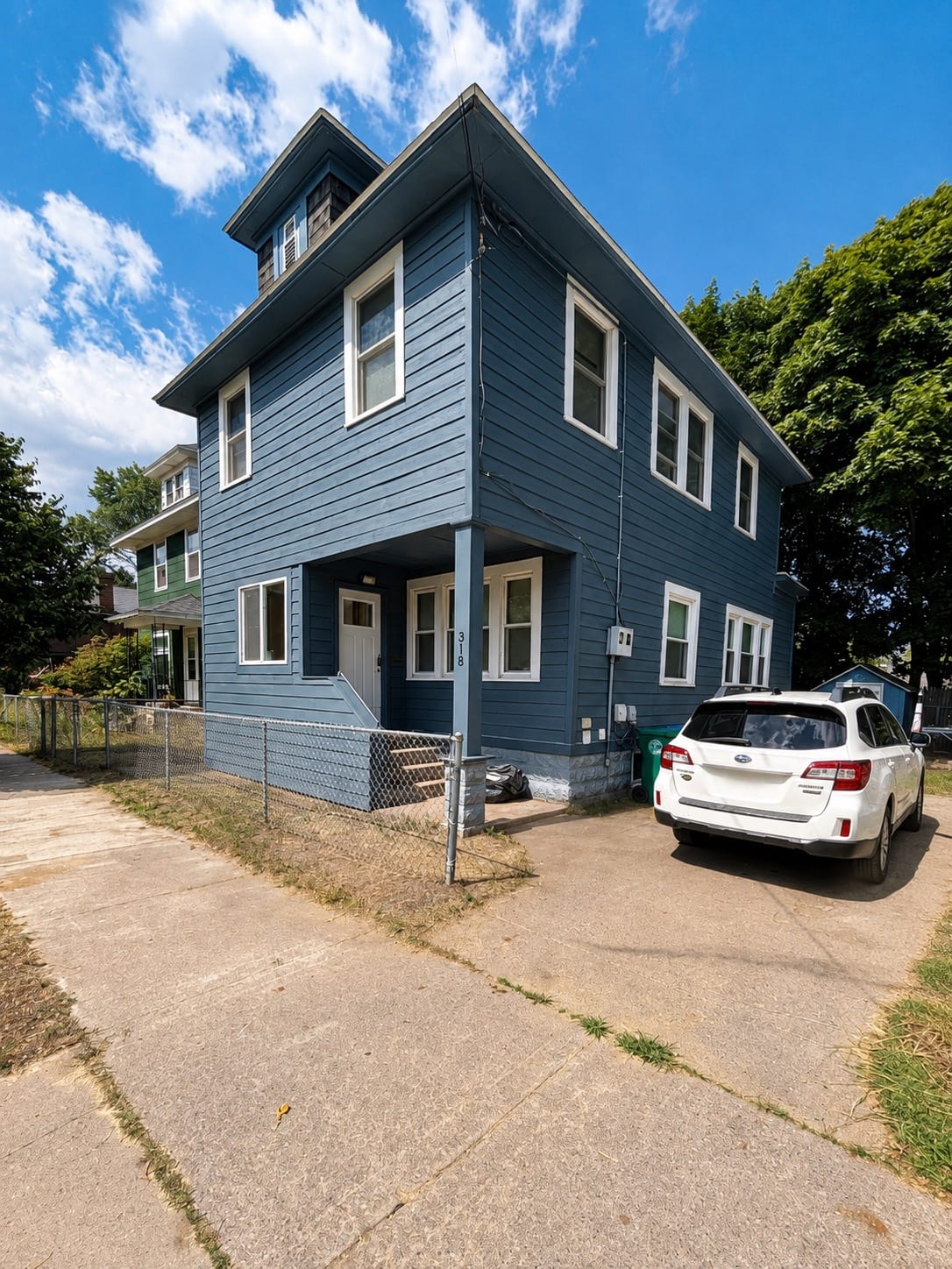 The same house after siding work: new blue lap siding with white window trim and a repainted porch