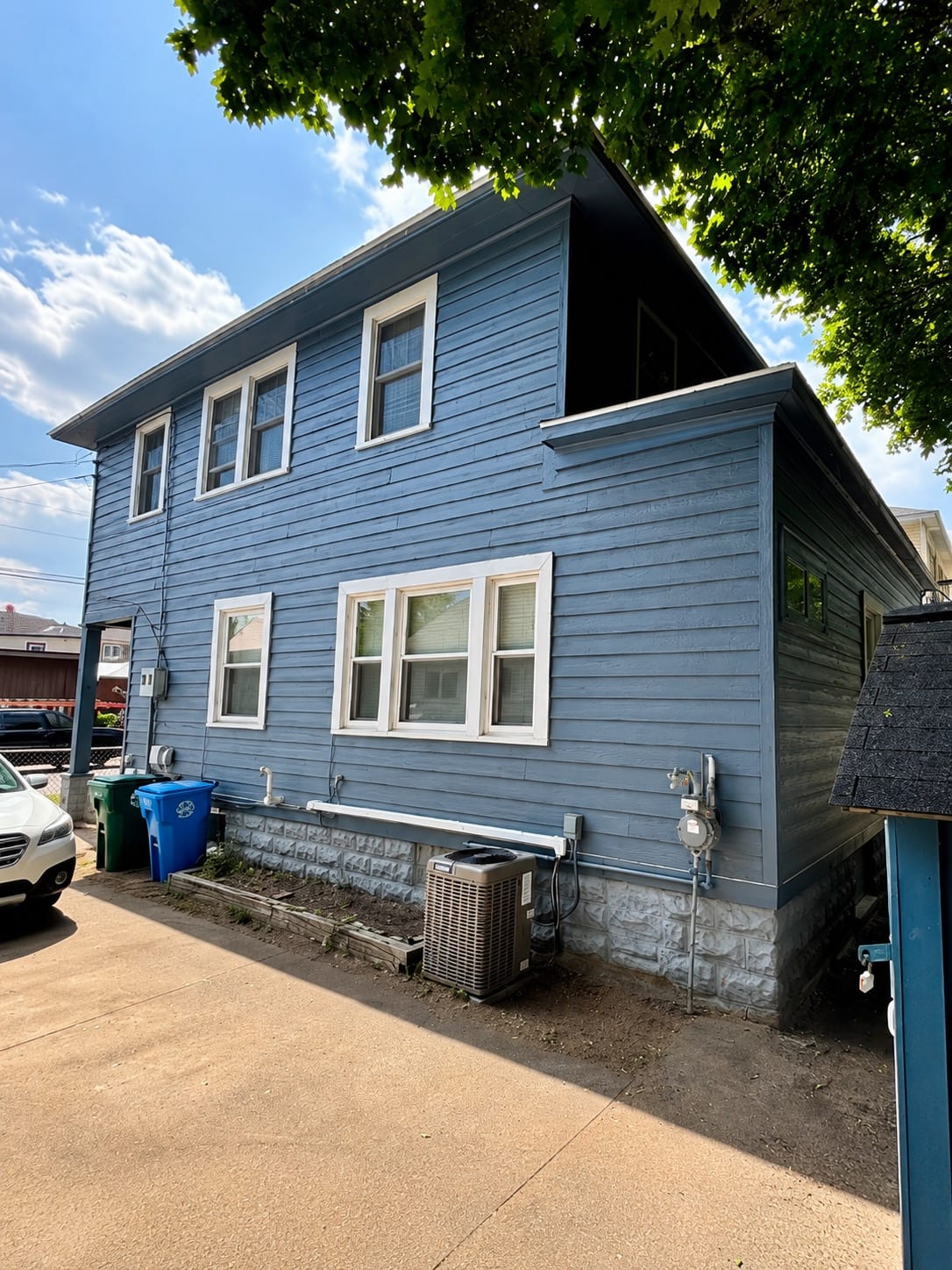 A two-story home with finished blue-gray lap siding and white window trim